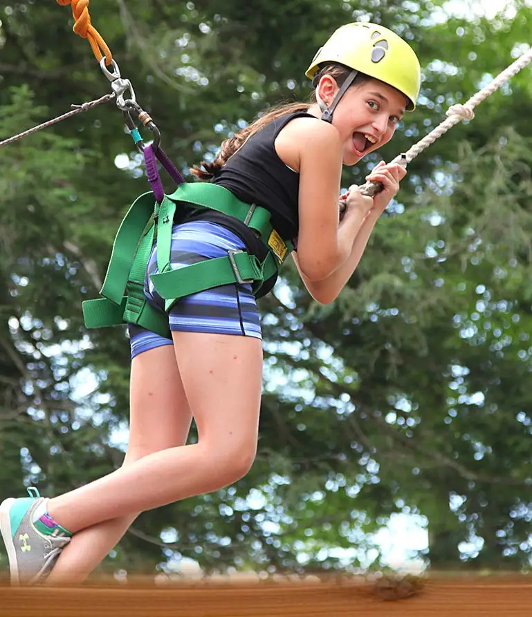 girl camper ziplining and smiling