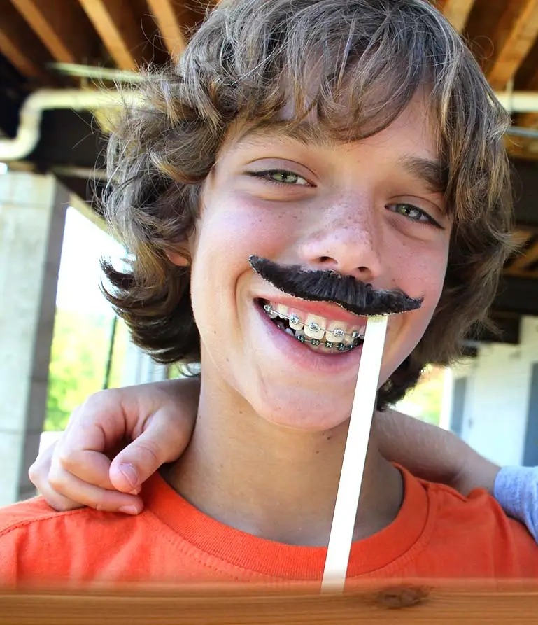 camper smiling wearing a fake moustache